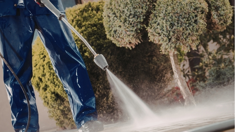 Person pressure washing driveway pavers outside a Sydney home
