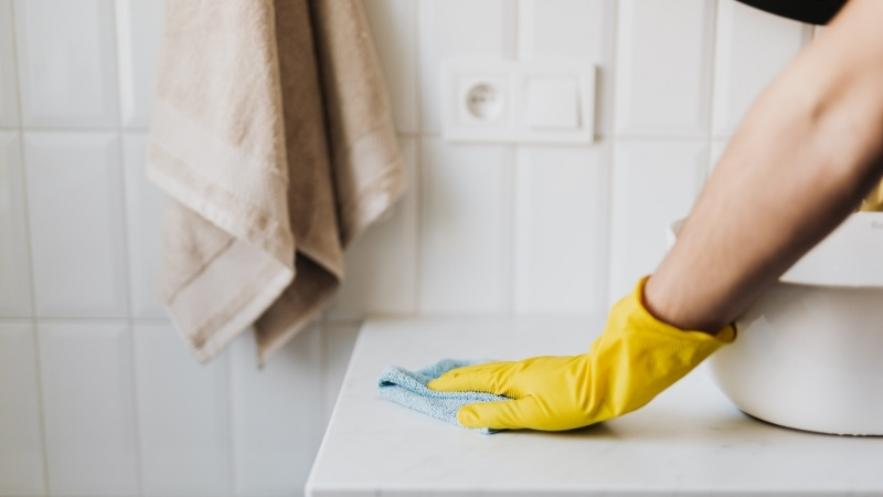 Cleaning bathroom surfaces with cloth and rubber gloves